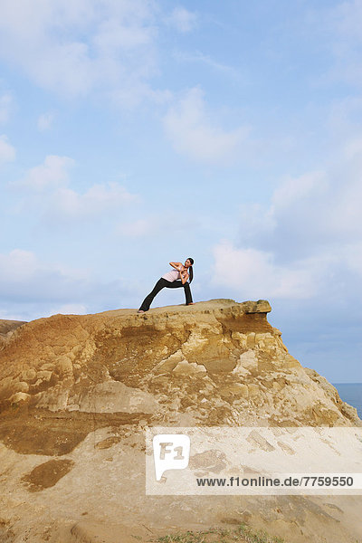 Woman practicing Yoga on a cliff