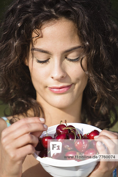 Portrait of a young woman holding a bowl of cherries