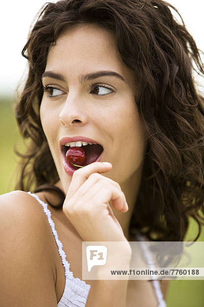 Young woman eating a cherry  oudoors