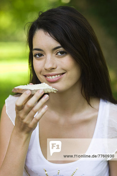 Junge Frau isst Brotscheibe mit Käse