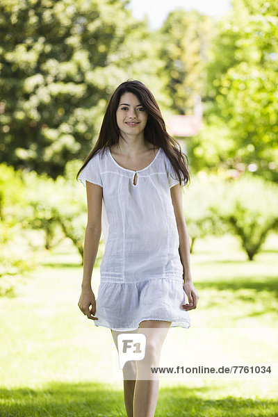 Junge Frau mit weißem Kleid in grüner Landschaft