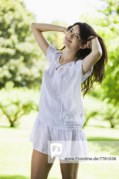 Junge Frau mit weißem Kleid in grüner Landschaft