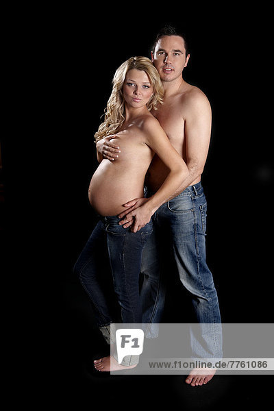 Man embracing topless pregnant woman