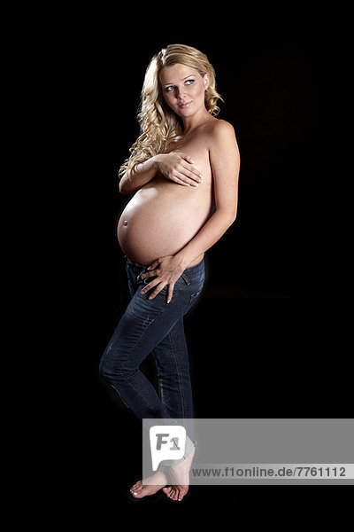 Oben-ohne schwangere Frau mit Händen  die die Brust bedecken.