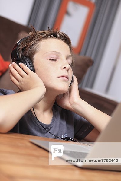 Frankreich  Junge  der mit dem Computer Musik hört.