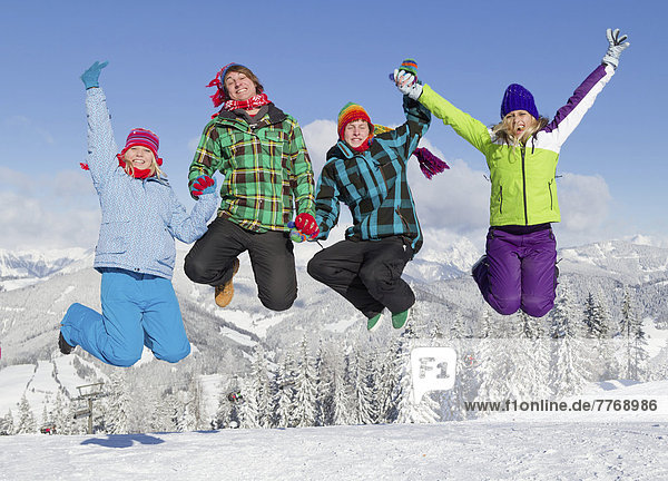 Gruppe von jungen Leuten im Sprung auf Skihang