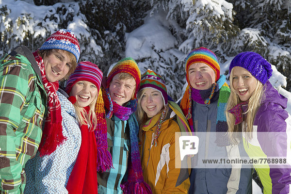 Gruppe von jungen Leuten vor verschneitem Fichtenwald