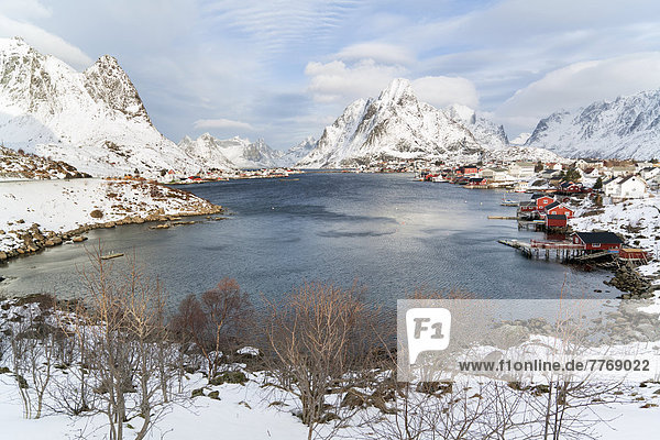Fishing village with red cottages beside a fjord in winter