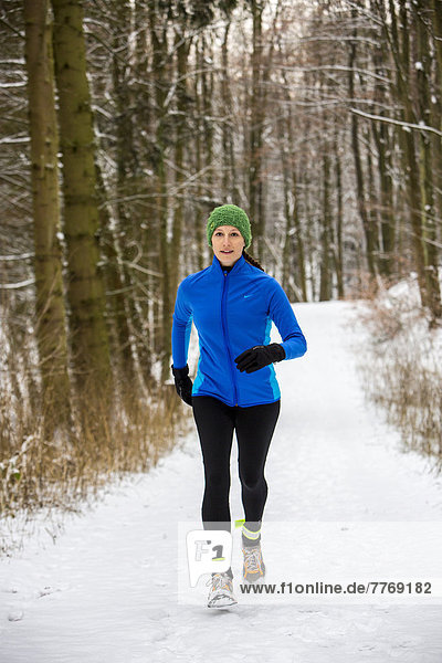 Female jogger on a run in a snow-covered forest  in winter