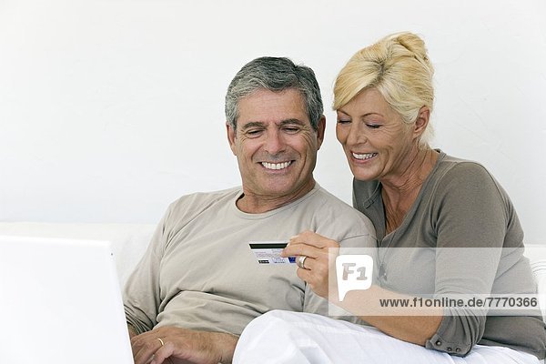 Erwachsenes Paar mit Laptop  Frau mit Kreditkarte