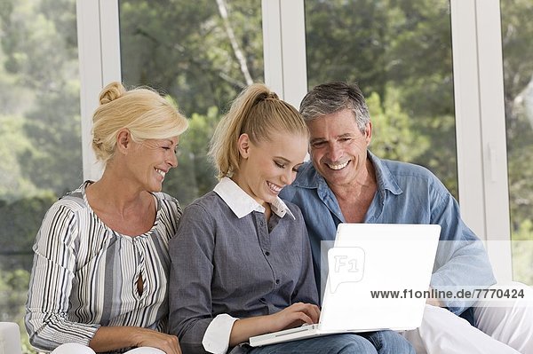 Mature couple and young woman using laptop