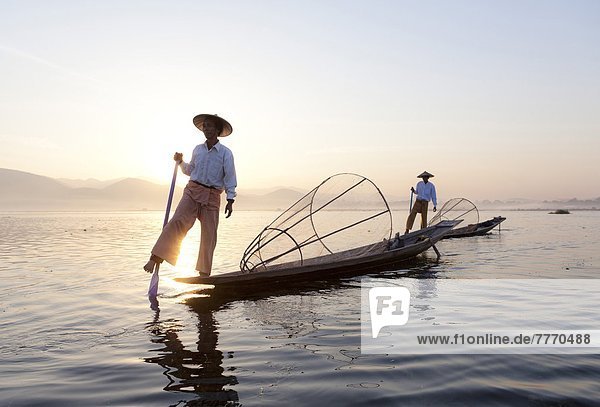 Intha leg rowing fishermen at dawn on Inle Lake who row traditional wooden boats using their leg and fish using nets stretched over conical bamboo frames  Inle Lake  Shan State  Myanmar (Burma)  Asia