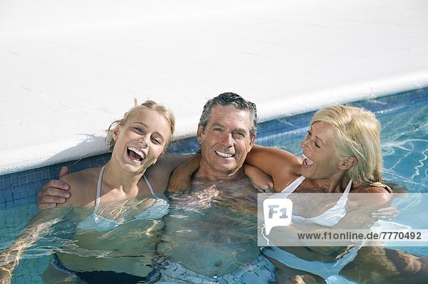 Seniorenpaar und junge Frau posieren im Pool