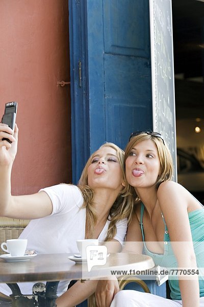Two young women taking a self portrait with mobile  outside