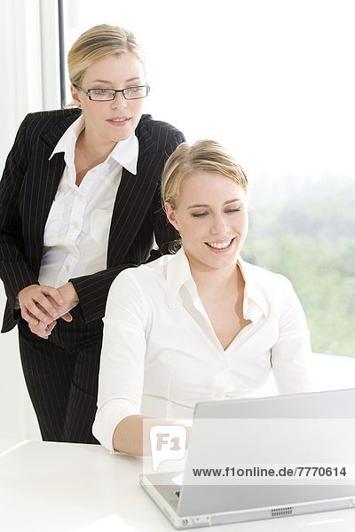 Businesswoman supervising woman using laptop computer