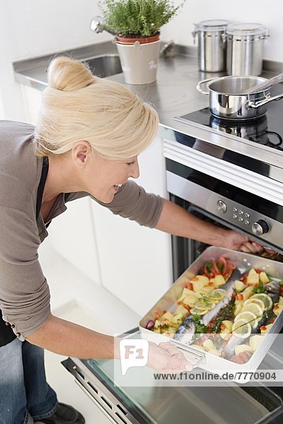 Reife Frau beim Kochen von Fisch