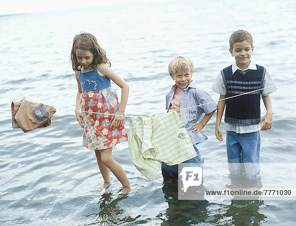 3 children playing at lake edge
