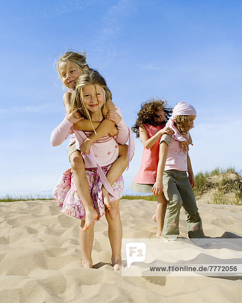 Vier kleine Mädchen spielen am Strand