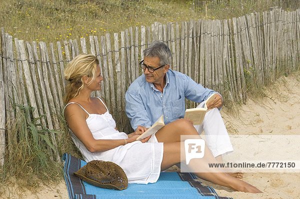 Paar beim Lesen eines Buches am Strand