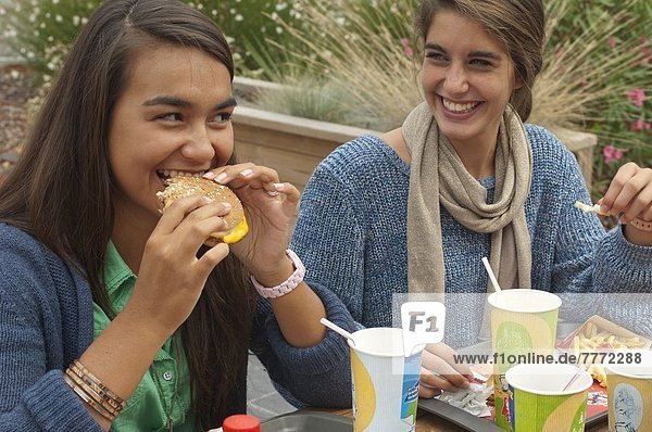 Teenager trinken Erfrischungsgetränke und essen Hamburger