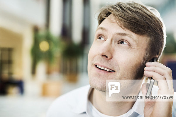 Mid adult businessman looking up while using mobile phone