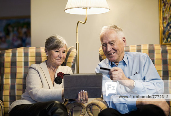Seniorenpaar mit Kreditkarte und digitalem Tablett zum Online-Shopping