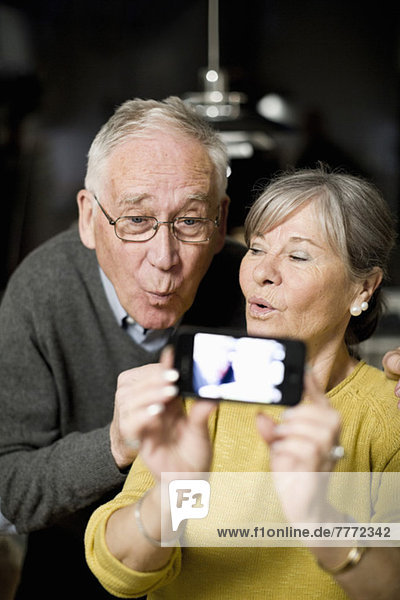 Senior couple making faces while taking self portrait through mobile phone