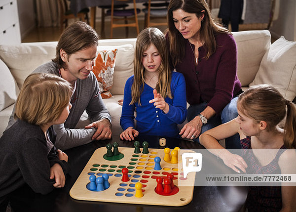 Family of five playing ludo together at table