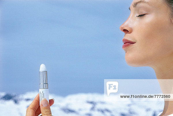 Porträt einer jungen Frau  die einen Stock hält  Augen geschlossen  schneebedeckte Berge hinten  Seitenansicht  blauer Himmel  Mund