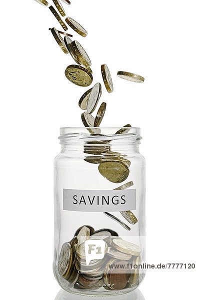 Savings jar with coins pouring into it  UK currency