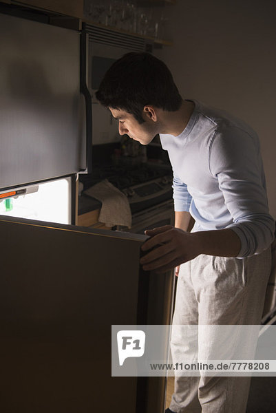 Man opening fridge at night
