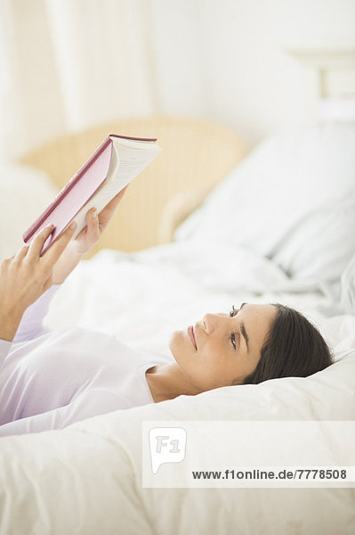 Woman lying in bed and reading book