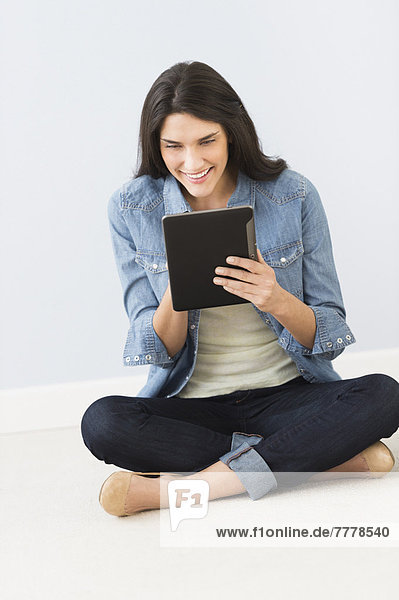 Woman sitting on floor and using digital tablet