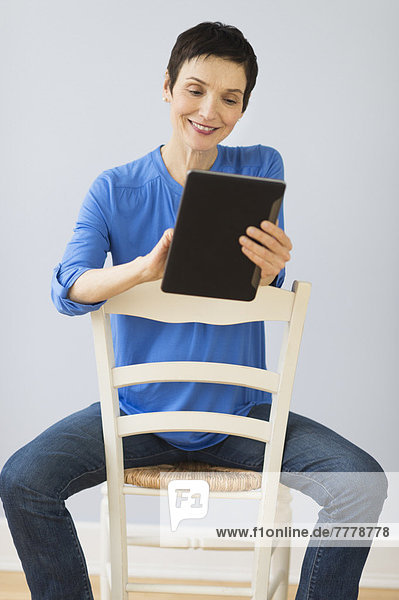 Woman sitting on chair and using digital tablet