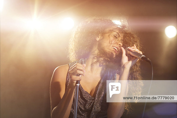 Young woman singing in spotlight
