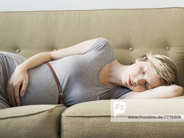 Pregnant woman lying on sofa sleeping