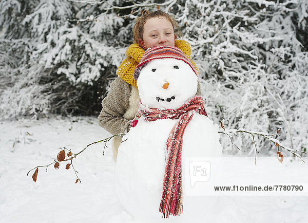 Mädchen macht Schneemann im Freien