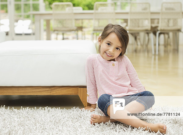 Lächelndes Mädchen auf einem Teppich sitzend