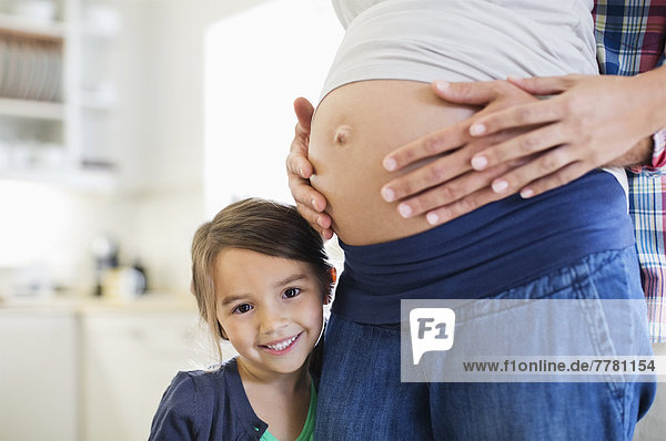Mädchen lächelt mit schwangeren Mutterbauch