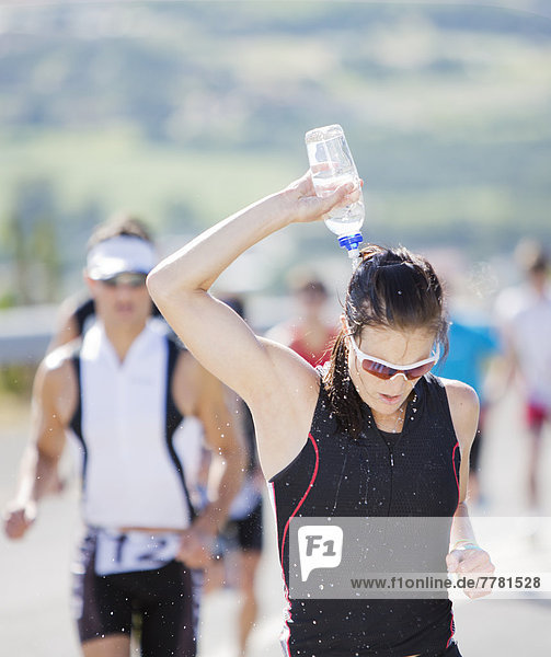 Läufer gießt Wasser auf den Kopf im Rennen