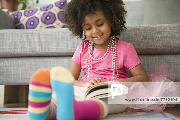 African American girl reading in living room