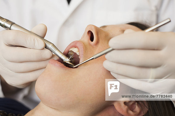 Caucasian dentist examining woman's teeth in office