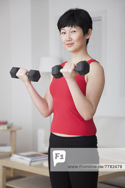 Woman lifting weights in living room