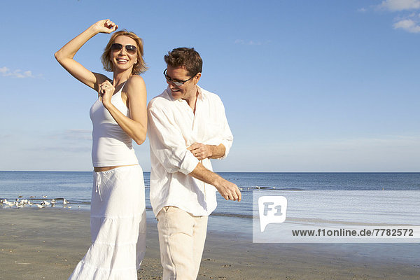 Caucasian couple dancing on beach