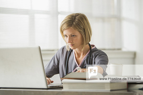 Caucasian nurse using laptop in doctor's office