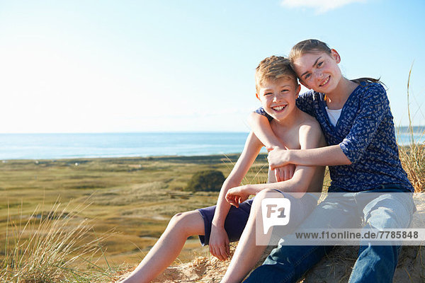 Boy and teenage girl sitting on beach