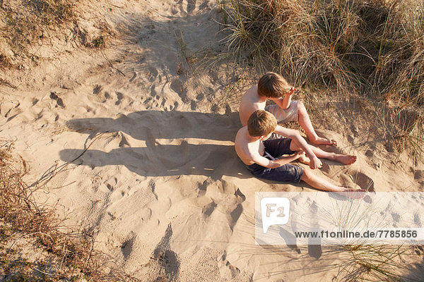 Two boys sitting on beach  high angle