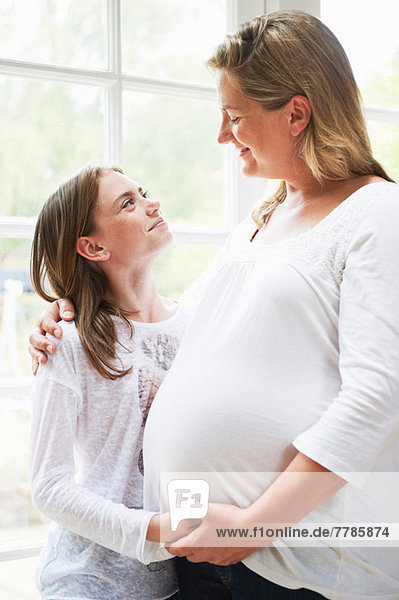 Schwangere Mutter mit jugendlicher Tochter am Fenster