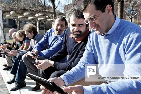 Mature businessman using digital tablet as colleagues look on