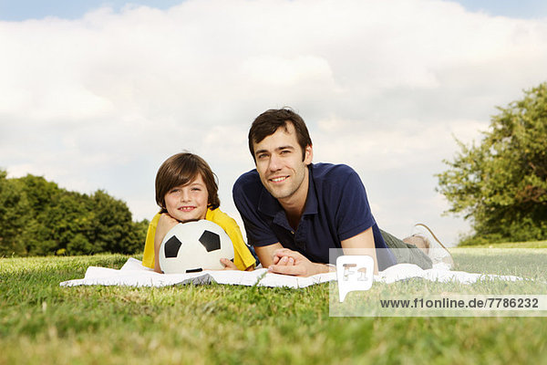 Vater und Sohn auf der Decke liegend mit Fußball